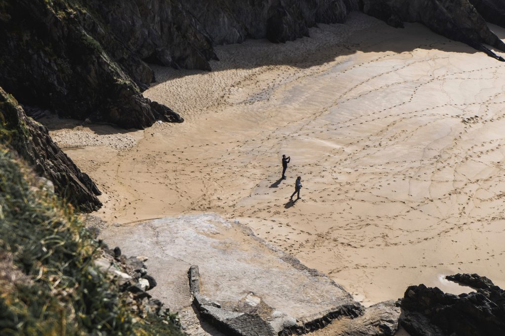 two people walking on a beach and footprints in the sand